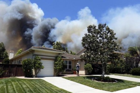 A man talks on a phone as a wildfire is seen approaching the neighborhood in Carlsbad, May 14, 2014.
